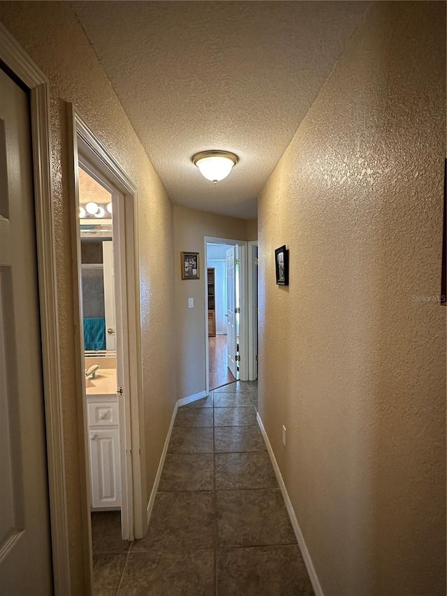 hallway with dark tile patterned flooring and a textured ceiling