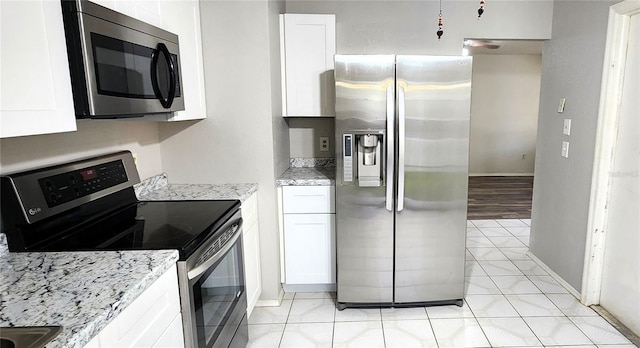 kitchen featuring light stone counters, stainless steel appliances, light tile patterned flooring, and white cabinetry