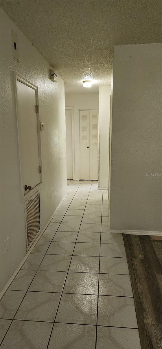 hallway with a textured ceiling and light tile patterned flooring