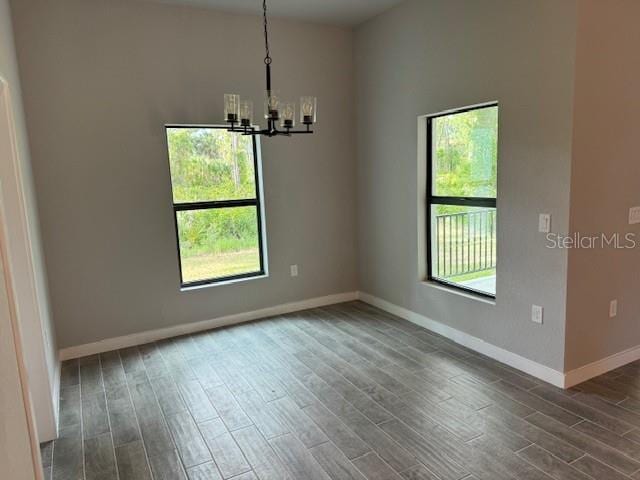 spare room featuring an inviting chandelier and dark hardwood / wood-style floors