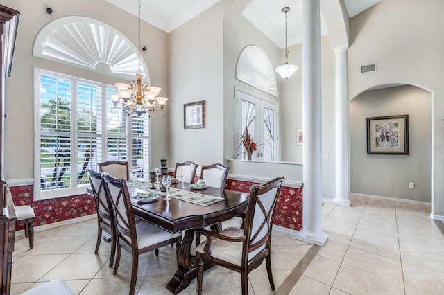 tiled dining area with an inviting chandelier, ornamental molding, and decorative columns