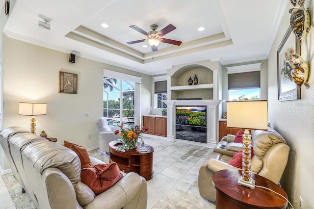 living room featuring a tray ceiling, ornamental molding, and built in features