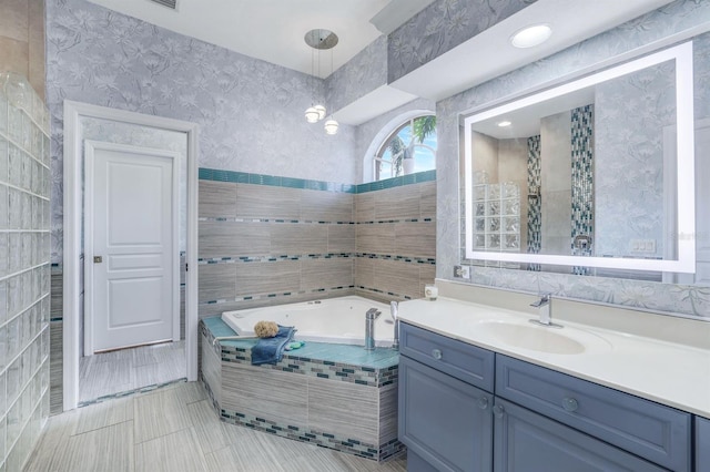 bathroom featuring vanity, tiled bath, and tile patterned flooring