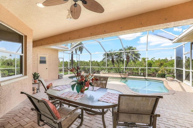 exterior space featuring a patio, ceiling fan, and glass enclosure