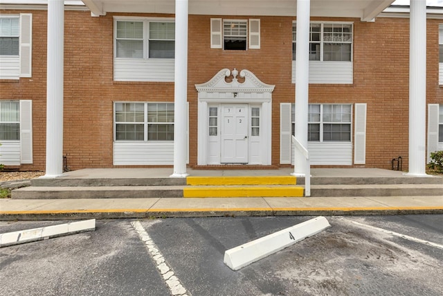 property entrance featuring uncovered parking, brick siding, and a porch