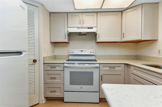 kitchen featuring gray cabinets, light countertops, light wood-style floors, white appliances, and under cabinet range hood