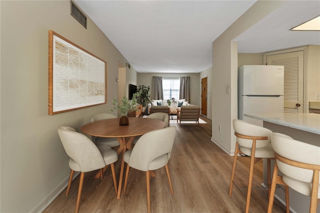 dining area featuring baseboards, visible vents, and wood finished floors