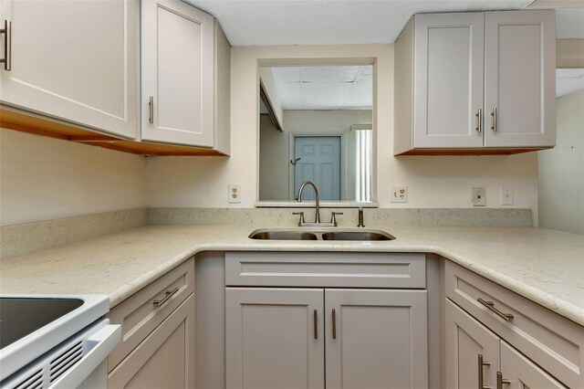 kitchen featuring a paneled ceiling, white cabinets, light countertops, and a sink