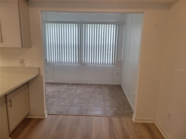 unfurnished dining area featuring light wood finished floors and baseboards