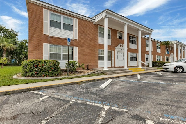 view of front facade with uncovered parking and brick siding