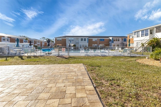 view of community featuring a residential view, fence, a pool, and a yard