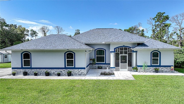 view of front of house with roof with shingles, a front yard, and stucco siding