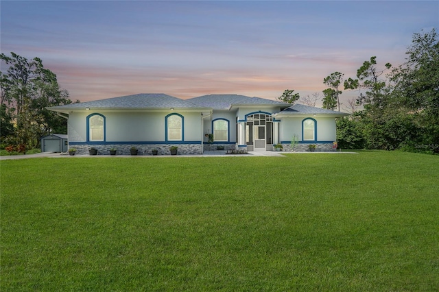 view of front facade featuring an outbuilding, a lawn, and stucco siding