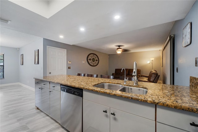 kitchen with light wood-type flooring, dishwasher, stone countertops, and sink