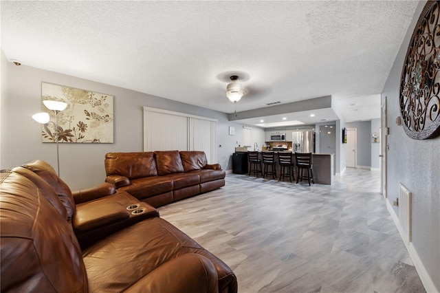 living room featuring ceiling fan and a textured ceiling