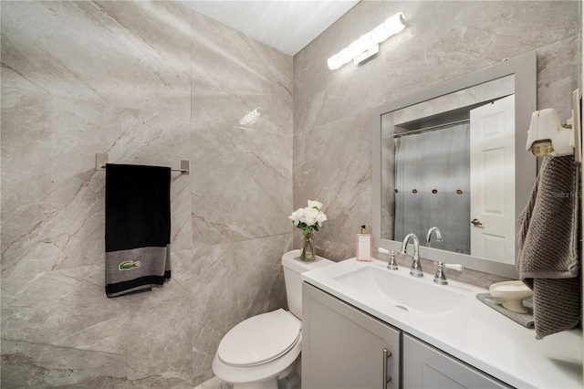 bathroom with vanity, tile walls, toilet, and a shower