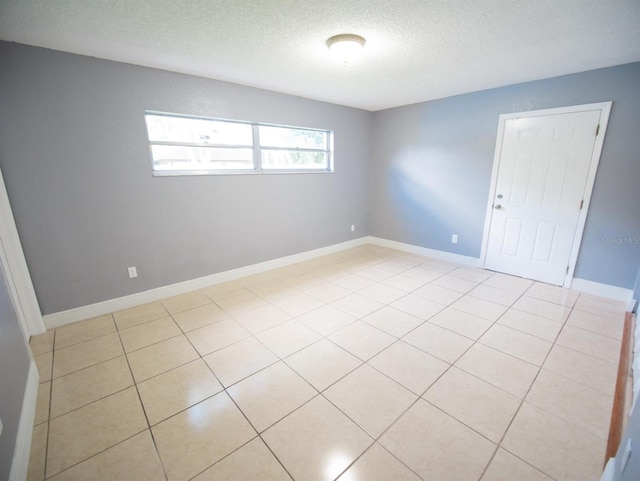 tiled empty room featuring a textured ceiling