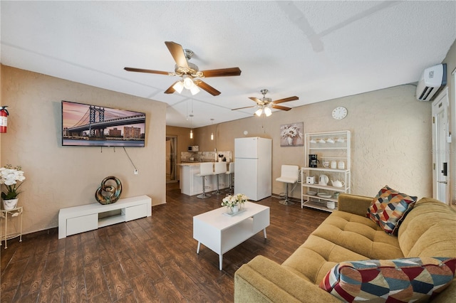 living room with a wall mounted AC, ceiling fan, dark hardwood / wood-style flooring, and a textured ceiling