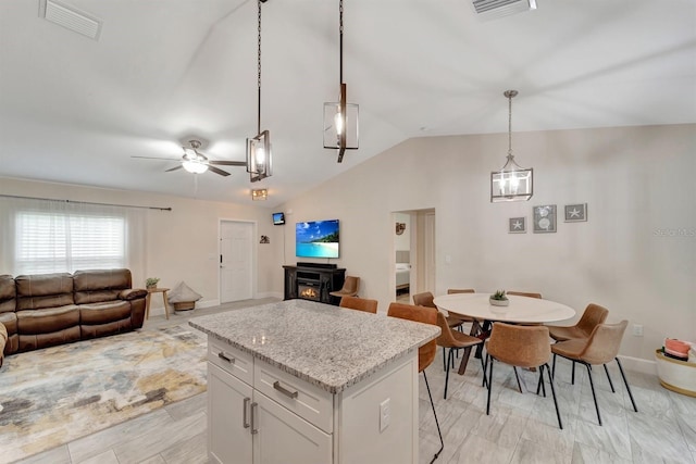 kitchen featuring white cabinetry, a kitchen island, ceiling fan, light stone countertops, and pendant lighting