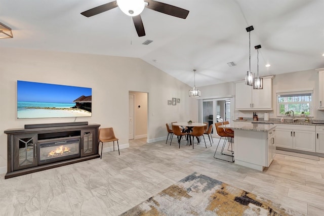 living room featuring sink, ceiling fan, vaulted ceiling, and light tile patterned floors