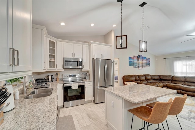 kitchen with white cabinetry, a breakfast bar area, hanging light fixtures, appliances with stainless steel finishes, and sink