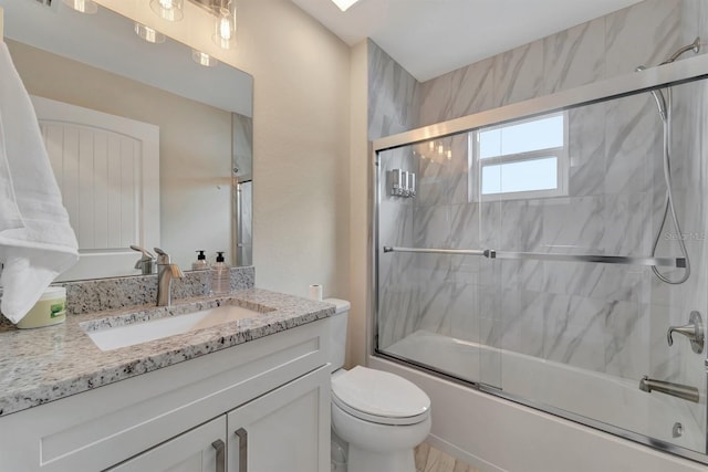 full bathroom with vanity, bath / shower combo with glass door, and toilet