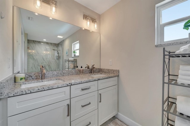 bathroom with tiled shower and dual vanity