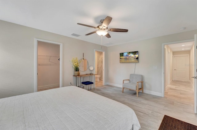 bedroom featuring a closet, light hardwood / wood-style flooring, a walk in closet, and ceiling fan