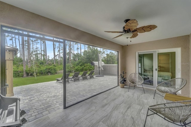 unfurnished sunroom featuring ceiling fan