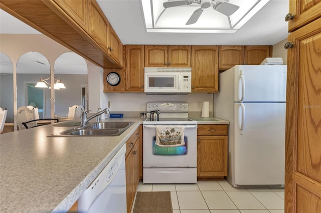 kitchen featuring white appliances, a ceiling fan, brown cabinets, and a sink