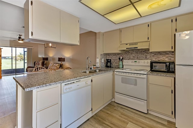 kitchen featuring under cabinet range hood, a sink, cream cabinets, white appliances, and a peninsula