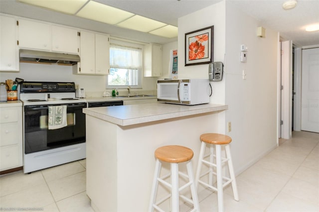 kitchen with white cabinets, light tile patterned floors, white appliances, kitchen peninsula, and a kitchen bar