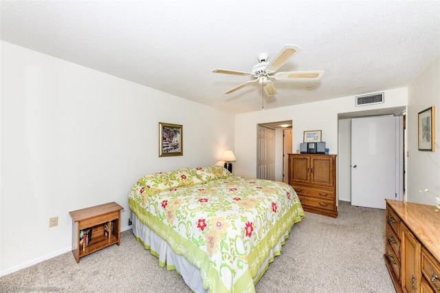 carpeted bedroom featuring ceiling fan and a textured ceiling