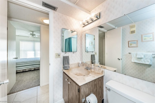 bathroom with a textured ceiling, vanity, toilet, tile patterned floors, and ceiling fan