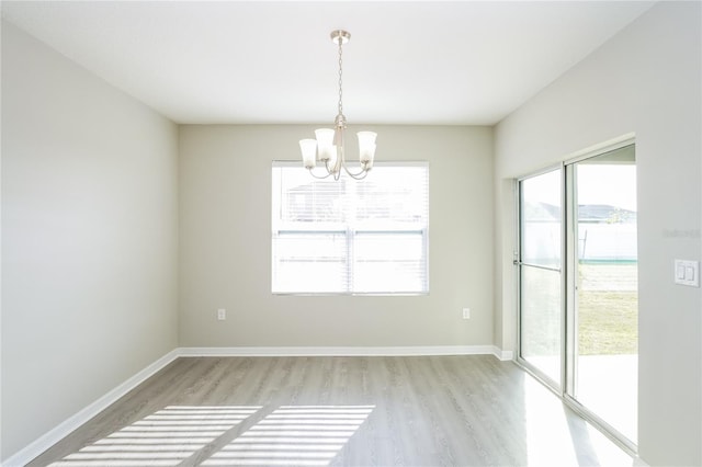 unfurnished room featuring a notable chandelier and light hardwood / wood-style floors