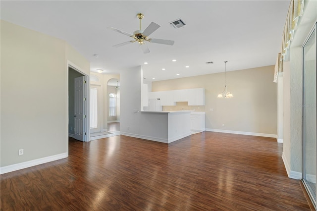 unfurnished living room with ceiling fan with notable chandelier and dark hardwood / wood-style flooring