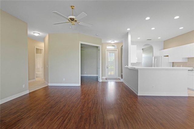 unfurnished living room featuring dark hardwood / wood-style flooring and ceiling fan