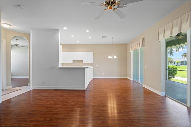 unfurnished living room with dark wood-type flooring and ceiling fan with notable chandelier