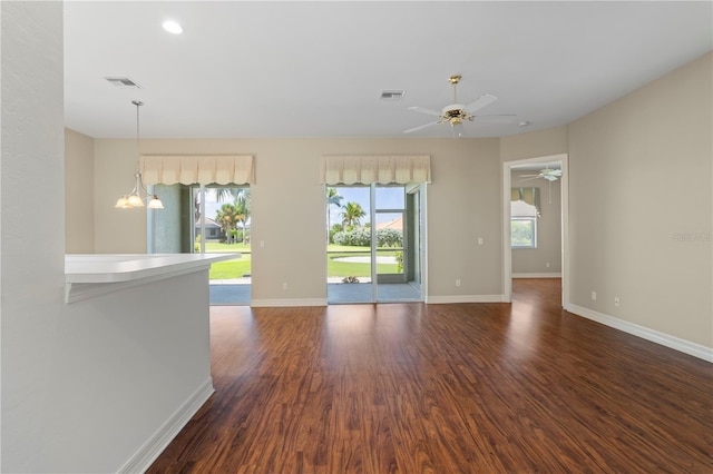 empty room featuring dark wood-type flooring and ceiling fan with notable chandelier