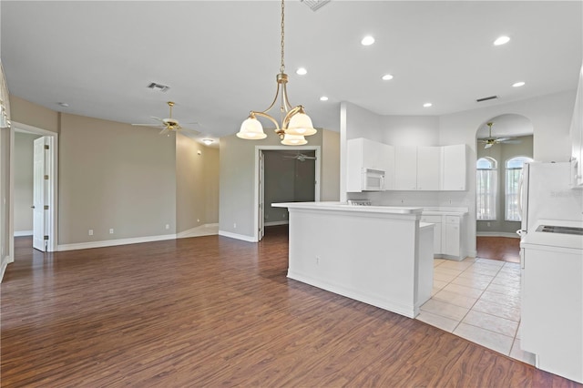 kitchen with white appliances, ceiling fan with notable chandelier, light hardwood / wood-style floors, white cabinets, and decorative light fixtures