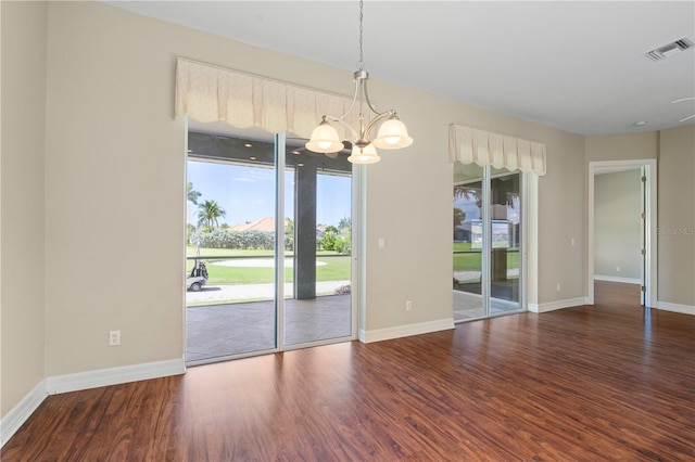 empty room featuring a notable chandelier and dark hardwood / wood-style floors