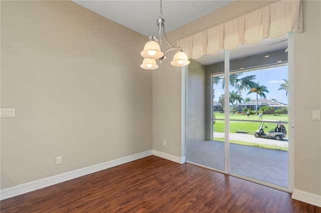 spare room featuring dark wood-type flooring and a chandelier