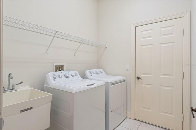 clothes washing area with sink, light tile patterned floors, and washing machine and dryer