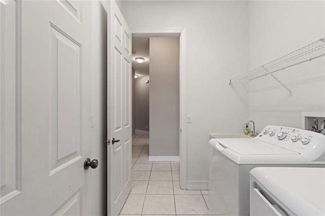 clothes washing area featuring sink, washing machine and dryer, and light tile patterned flooring