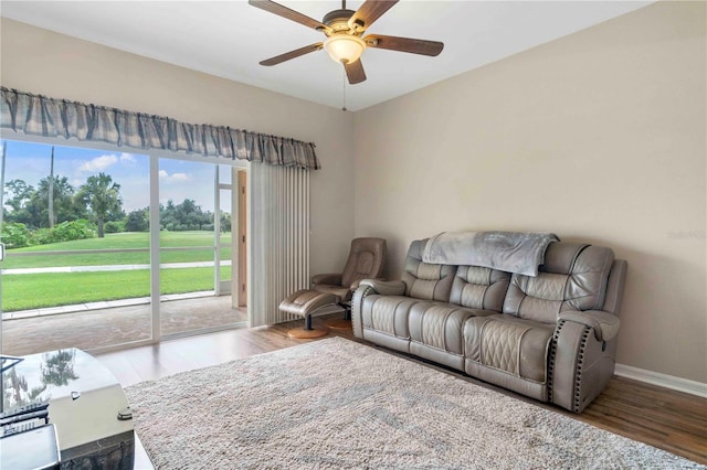 living room with a ceiling fan, baseboards, and wood finished floors