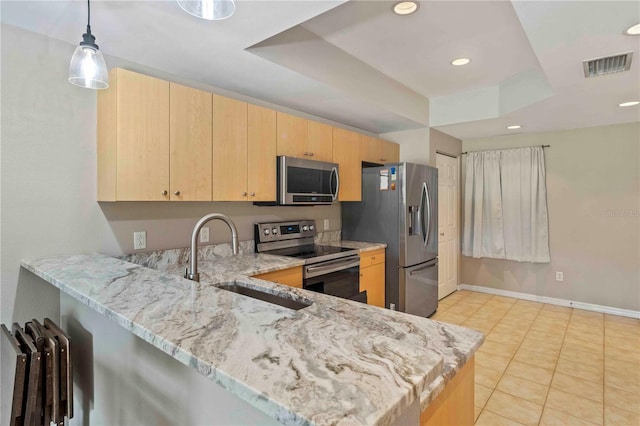 kitchen with light stone counters, appliances with stainless steel finishes, light brown cabinets, a sink, and a peninsula