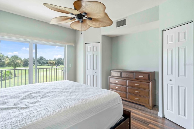 bedroom with dark wood-type flooring, visible vents, a ceiling fan, access to outside, and two closets