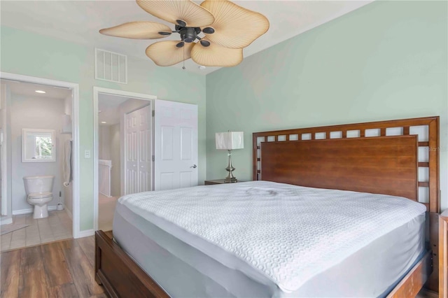 bedroom with ceiling fan, ensuite bathroom, dark hardwood / wood-style flooring, and a closet