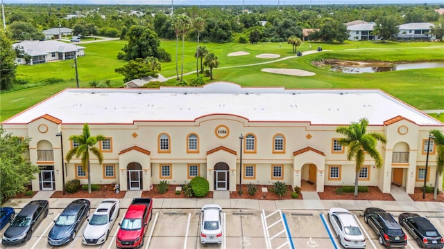 view of building exterior with uncovered parking, view of golf course, and a water view