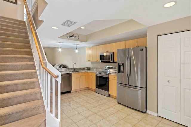 kitchen with light tile patterned flooring, appliances with stainless steel finishes, light brown cabinetry, sink, and a raised ceiling